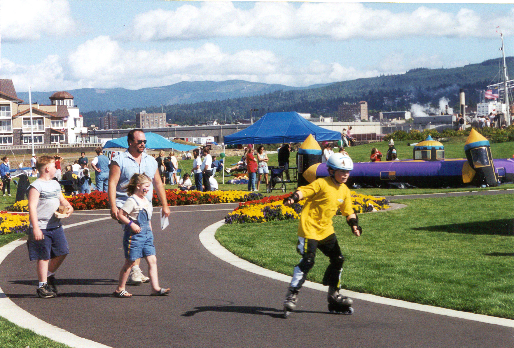 People walking and rollerblading at a festival in a park